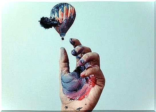 Hand with paint grips against hot air balloon