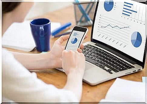 Woman at computer and phone looking at charts