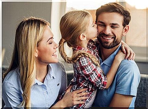 Girl kissing smiling dad with mom next to her