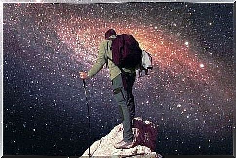 Man on cliff top looks out at starry sky