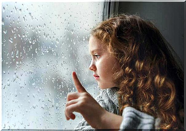 Little girl looking at rain on window