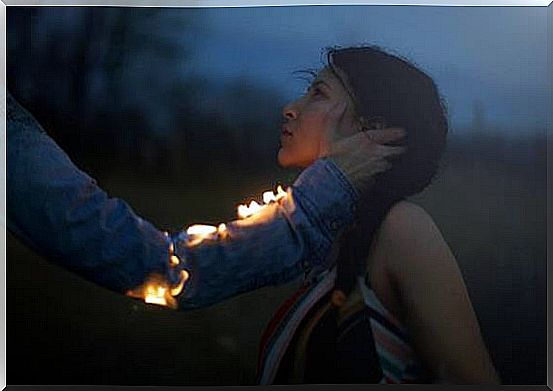 Man with fire in arm touches woman's face