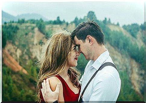 A couple in the summer hugging in front of mountains