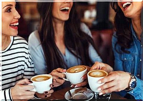 Three girlfriends sit down and have a cup of coffee