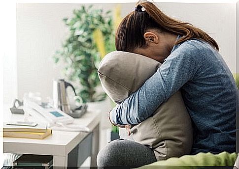 Woman hides face in pillow as a result of neuroticism