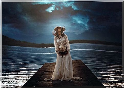 Woman standing on bridge by lake at night