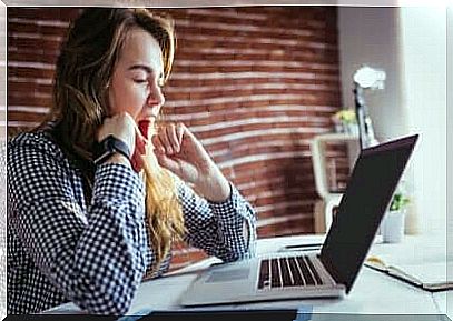 woman yawning in front of computer