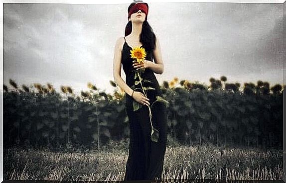 Woman with blindfold standing with sunflower