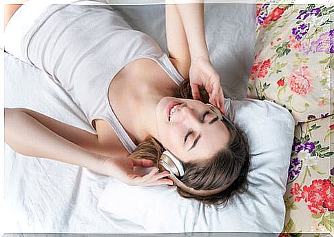 Woman lying on bed listening to music