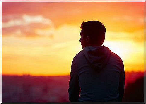 Man looking towards horizon with sunset