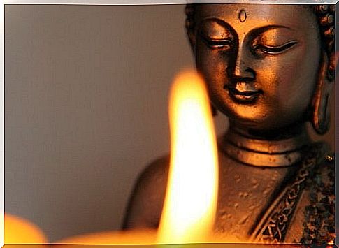 A Buddha statue in front of a candle