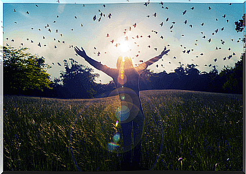 Woman with arms out to the sides and birds around her