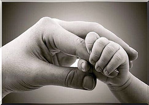 The baby's hand holds the mother's finger