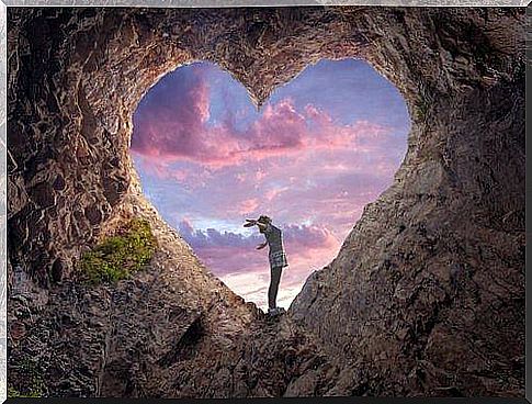 Woman standing in hole in mountain shaped like heart