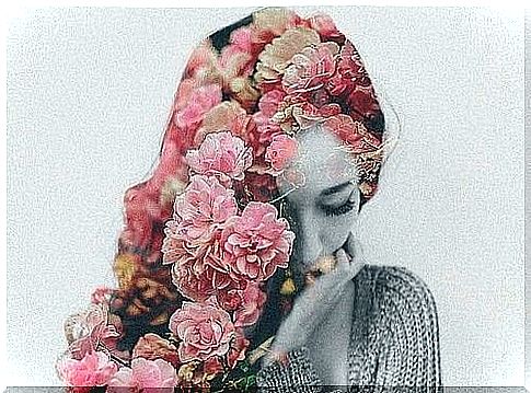 Woman with pink flowers in her hair shows how senses affect emotions as she is touched by the scent and color of the flowers